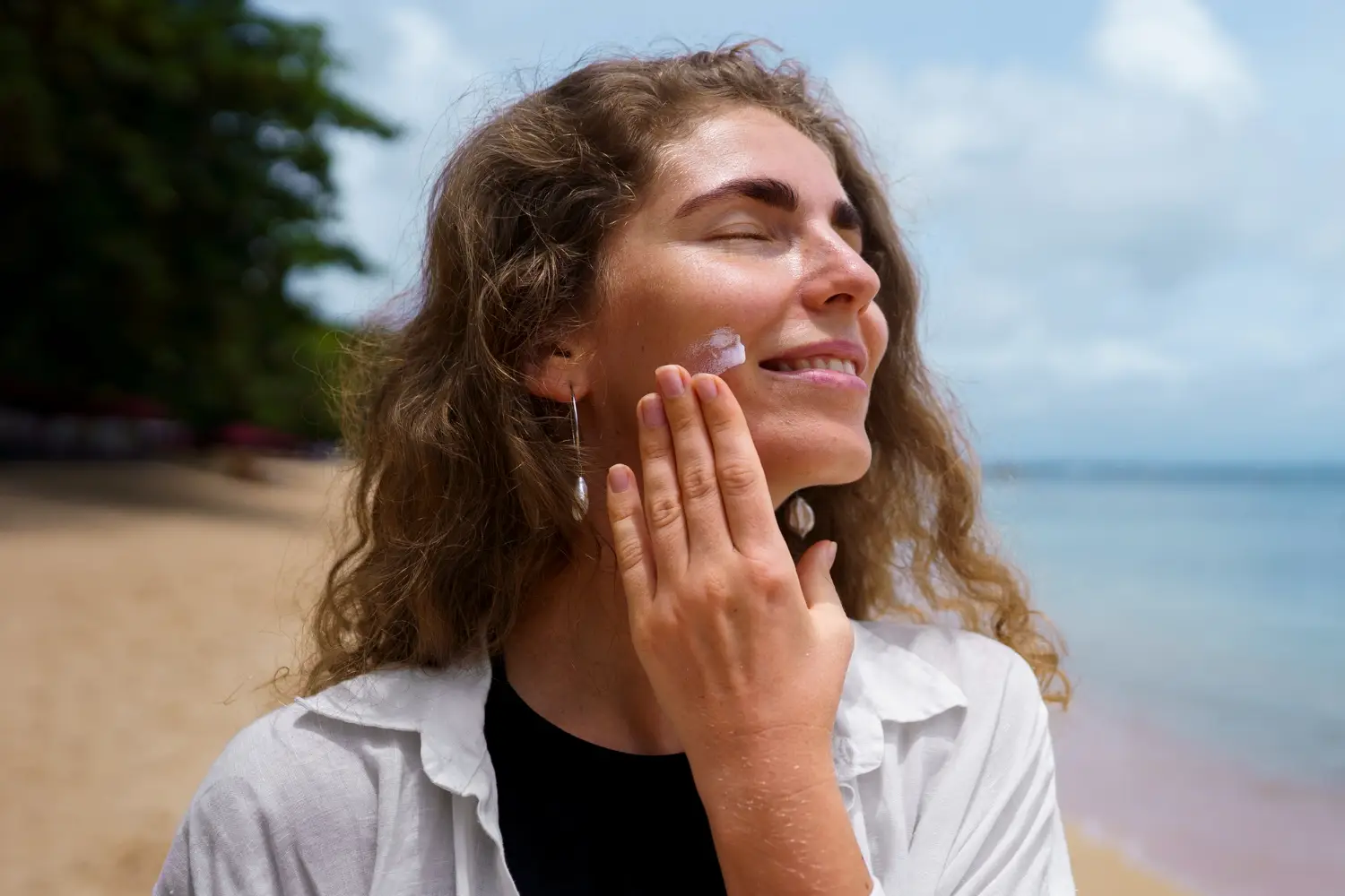 Person applying sunscreen on face showing importance of sunscreen even on cloudy days